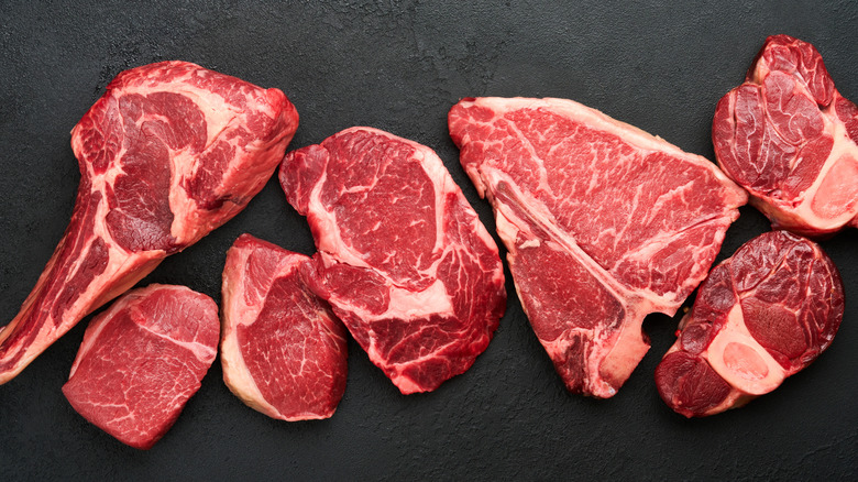 various cuts of raw USDA Prime steak set against a dark slate background