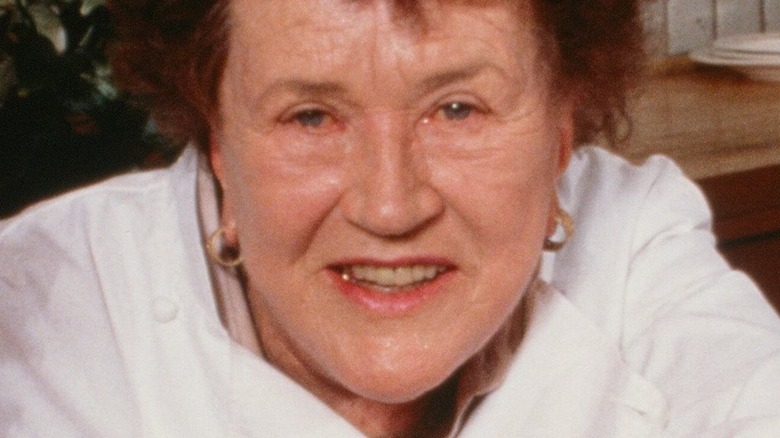 Julia Child smiling in front of plates of food