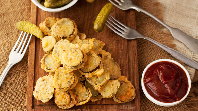 Fried pickles on a cutting board with a side of ketchup