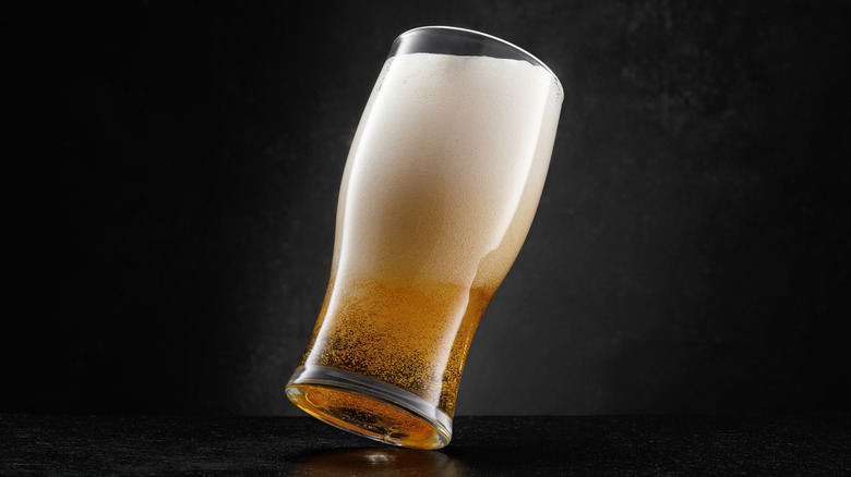 Beer with more foam than liquid in a glass on a dark background