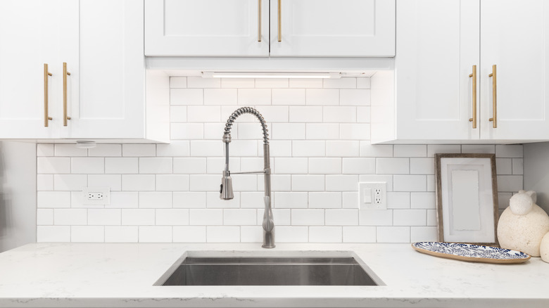 Kitchen sink with white backsplash and white cabinets