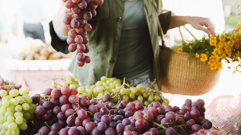 Hand grabbing red grapes at a farmer's market
