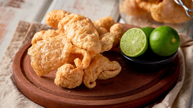 pork rinds on wooden platter with limes