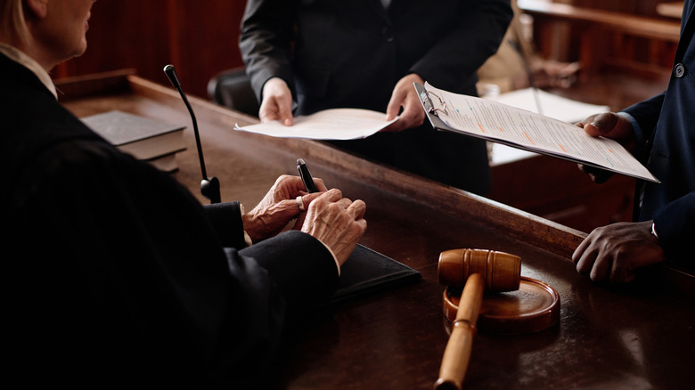 Courtroom scene at the judge's bench showing the hands the lawyers holding documents