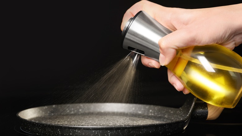 Hand spraying cooking oil in pan