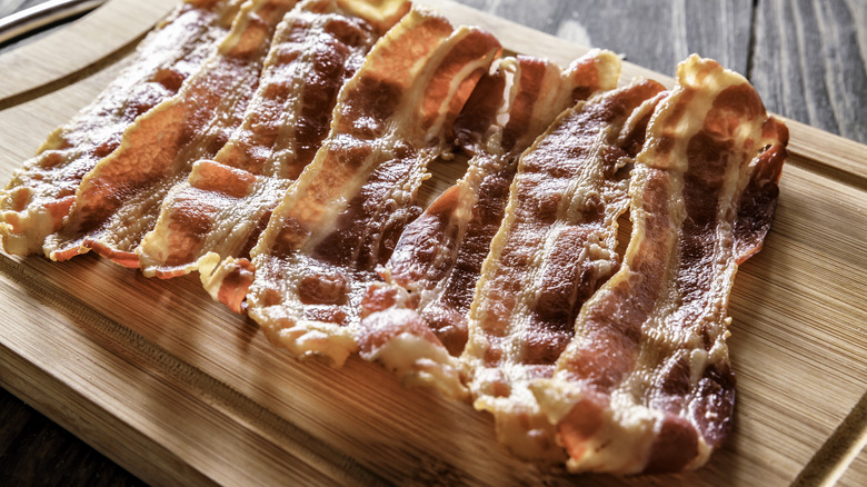 Strips of cooked bacon on board
