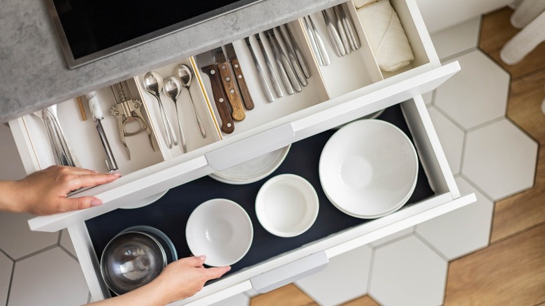 Hands organizing kitchen drawers with cubby inserts