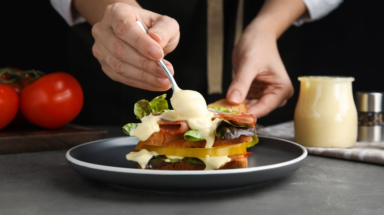 Spooning mayonnaise onto a sandwich