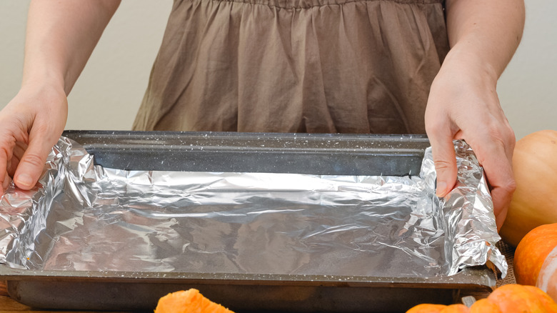 Person placing foil on pan