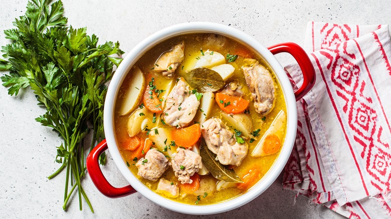 Chicken soup in red crock on granite counter with parsley 