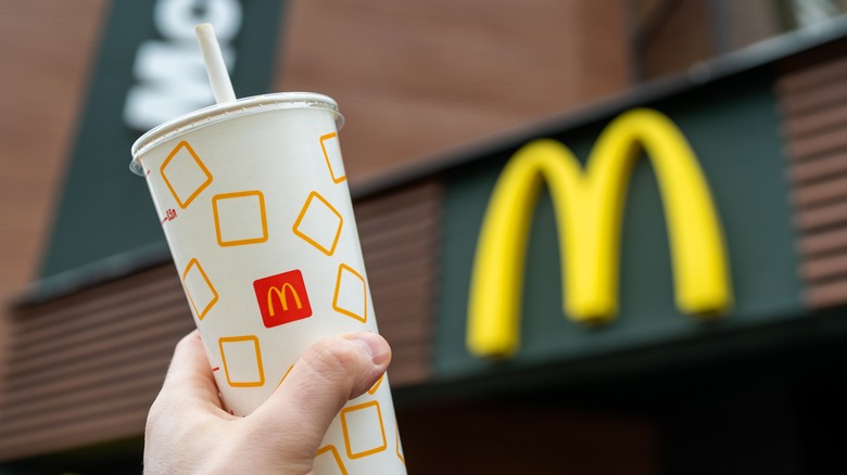 a person holding up a mcdonalds soda