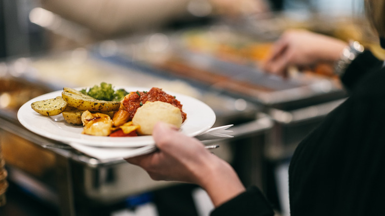 Someone holding a plat at a buffet, as they load it with food