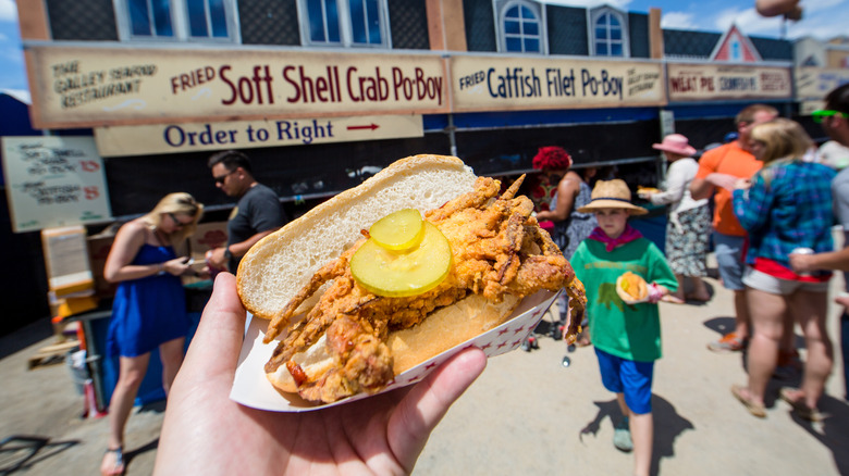 Hand holding a po-boy with a fried whole soft shell crab at New Orleans' Oak Street Po-Boy Festival