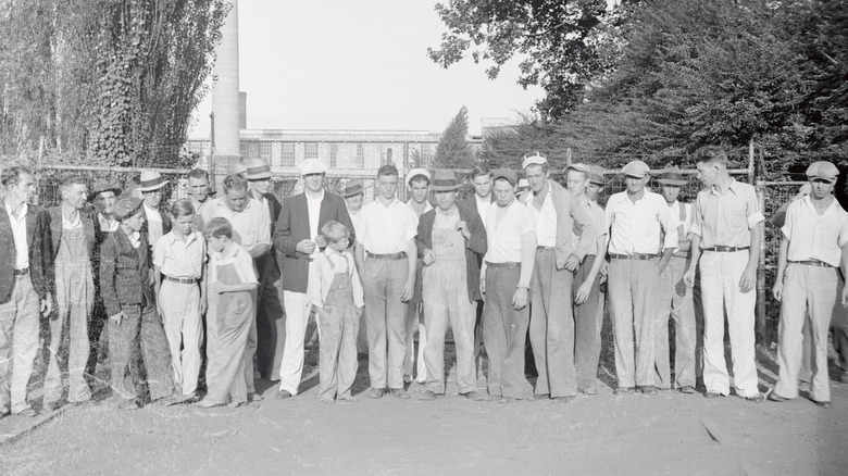 Black-and-white photo of workers standing outside factory during the Great Depression