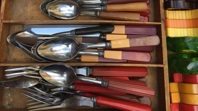 Drawer of vintage silverware with colorful bakelite handles.