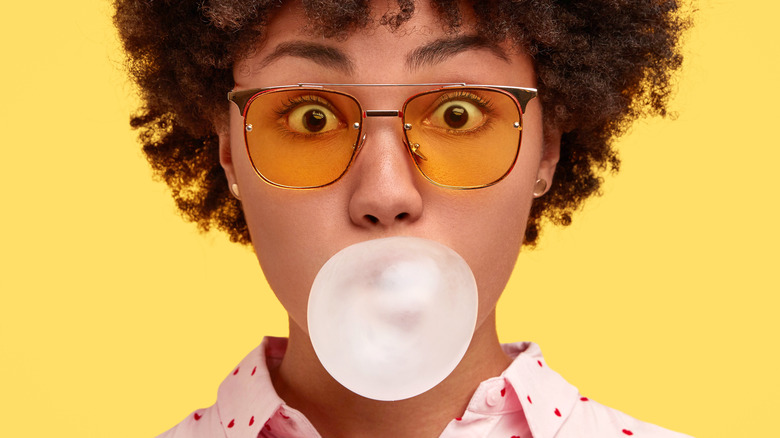 A woman blows a bubble of gum