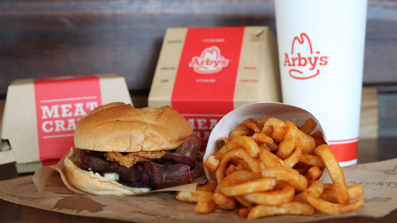 Arby's beef brisket sandwich on a table with french fries and a drink