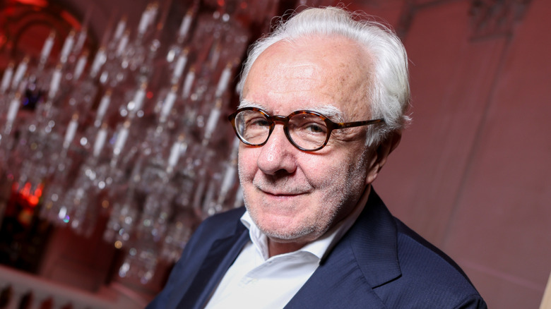 Alain Ducasse in dark suit and white shirt smiling to camera.