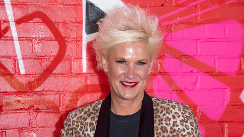 Anne Burrell in a leopard print blazer and black shirt smiling to camera.