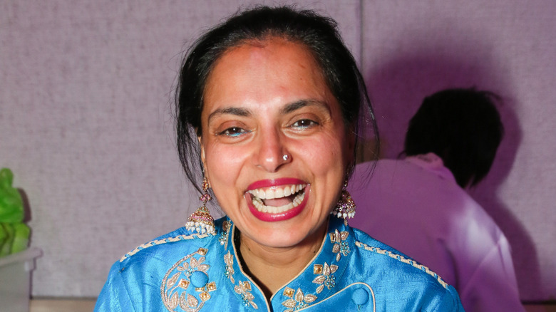 Maneet Chauhan smiling at the camera in a patterned blue chef's shirt.