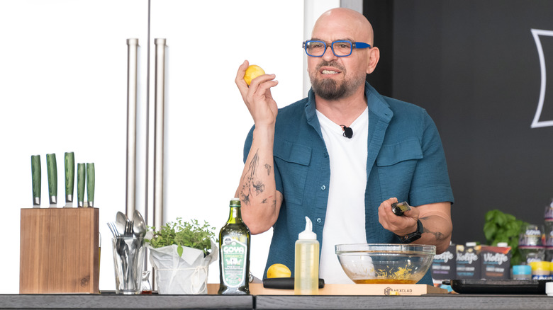 Michael Symon in a blue shirt holding up lemons.