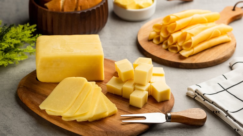 Wooden board with sliced and cubed cheese