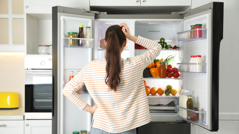 person looking inside open fridge