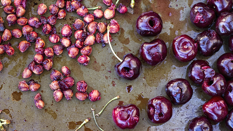 Pitted and whole cherries on flat surface
