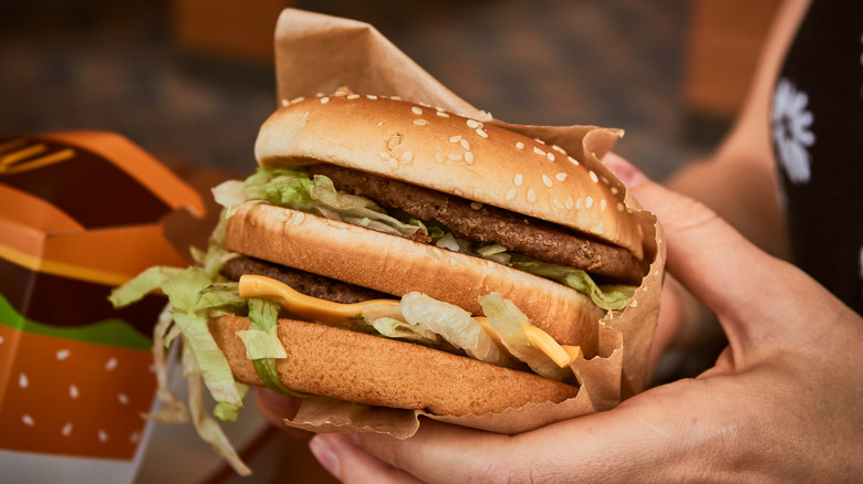 Close-up of partially-wrapped Big Mac burger in a diner's hands