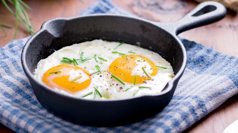fried eggs in a skillet with chives on top