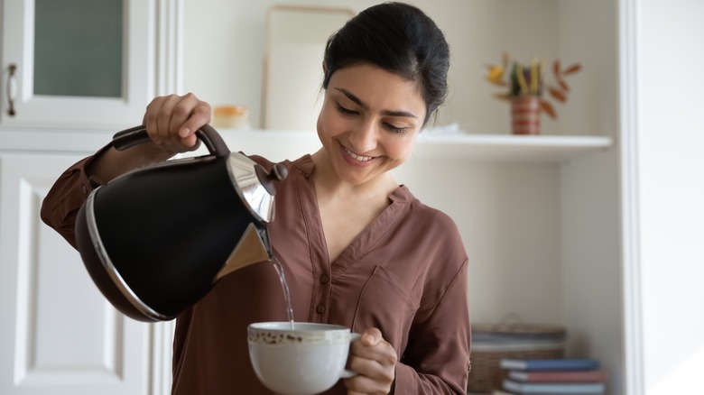 Woman pouring hot water into mug