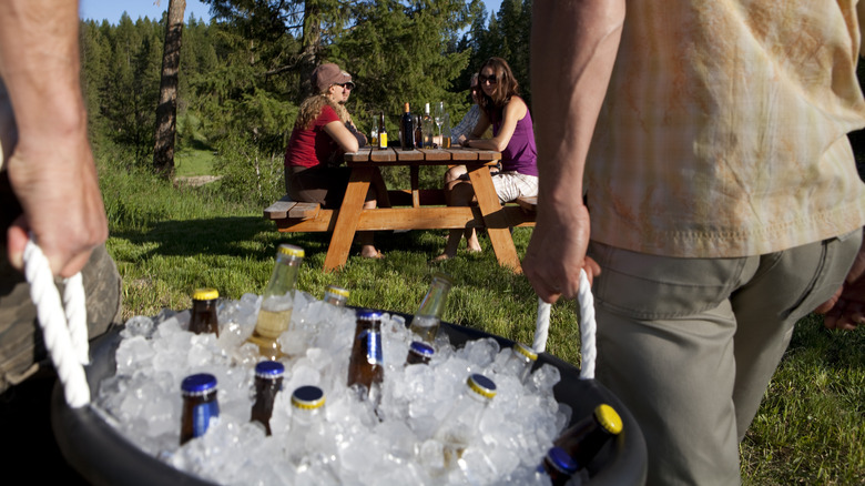 People carrying tub of beers on ice