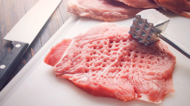 Pork chops being pounded