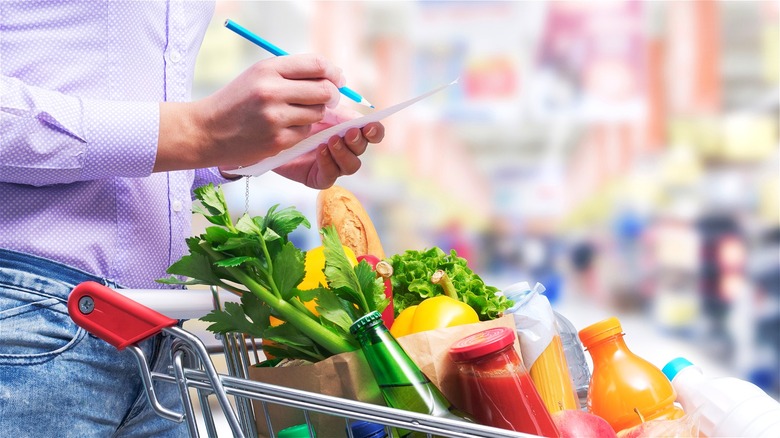 person with list over grocery cart