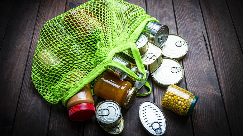 canned foods spilling out of reusable bag on wooden floor