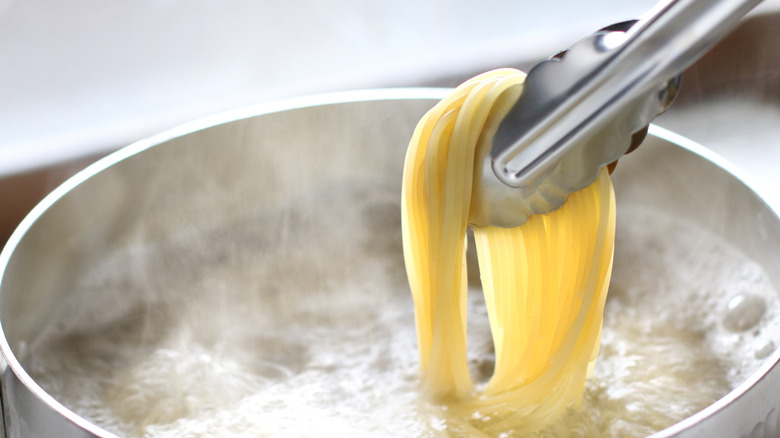 Kitchen tongs holding pasta