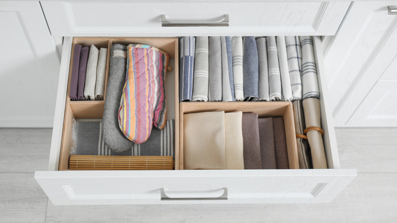 A kitchen drawer with several dish towels folded and stacked vertically