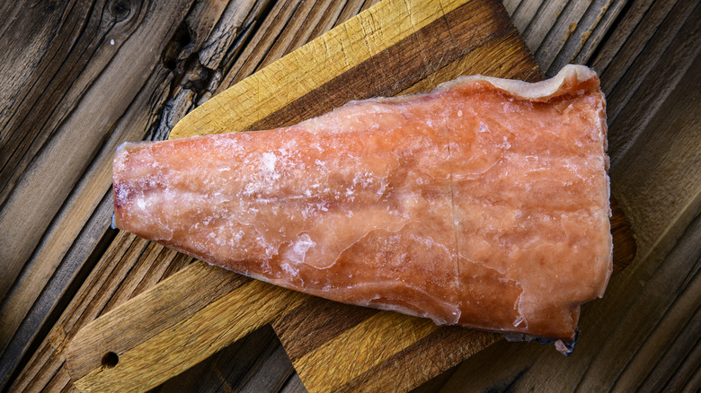 Piece of frozen salmon on wooden cutting board