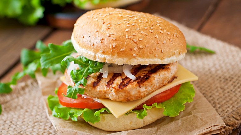 A grilled chicken sandwich on a brown napkin