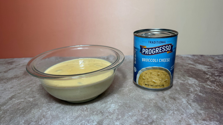 A bowl of Progresso broccoli cheese soup next to a sealed can showing the label