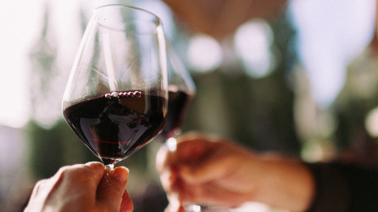 2 glasses of red wine held up for toast