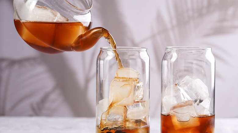 pouring tea into two glasses filled with ice
