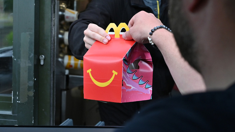 Employee handing Happy Meal box to drive-thru customer
