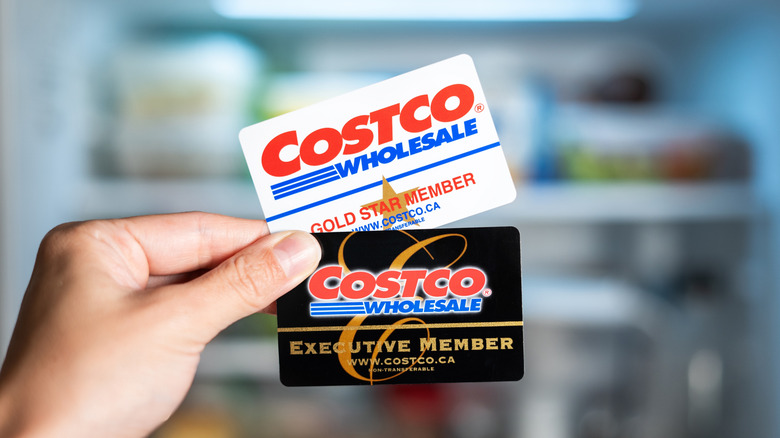 a hand holding two types of Costco membership cards