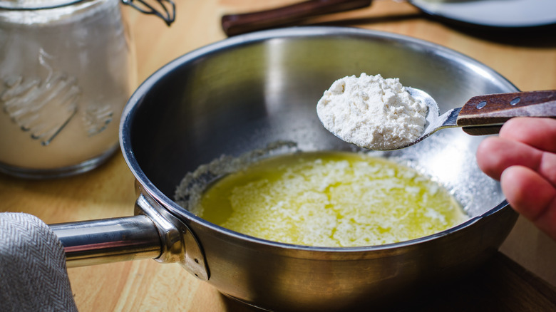 Person adding flour to butter