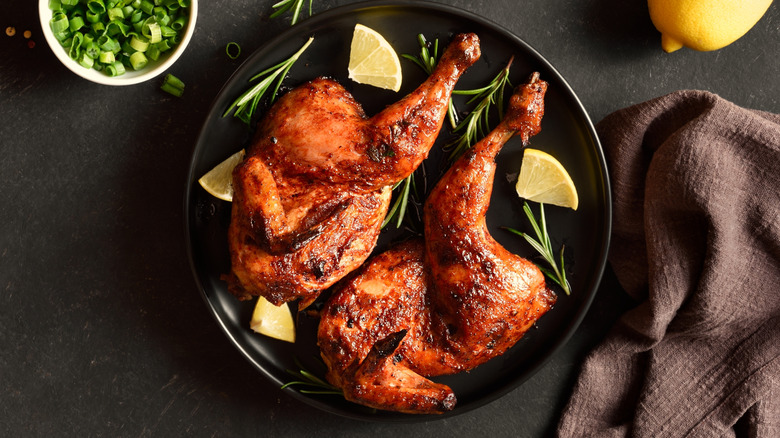 grilled split chicken on rustic background with seasonings