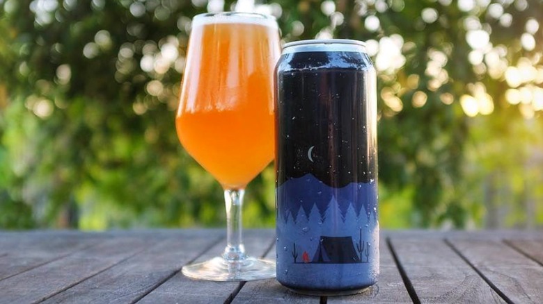 glass and can of Refuge IPA on table outside
