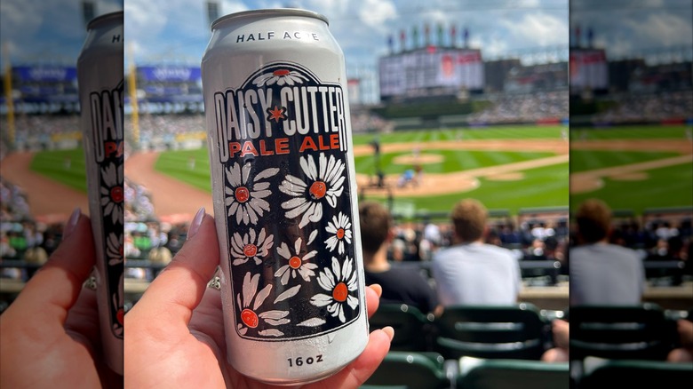 hand holding can of daisy cutter pale ale in baseball stadium stands