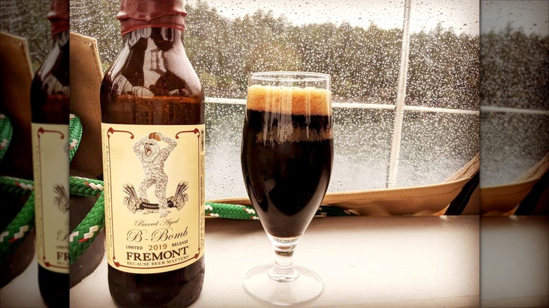 bottle and glass of b-bomb dark beer in front of rainy window