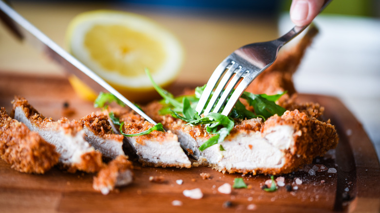 cutting into fried chicken schnitzel 